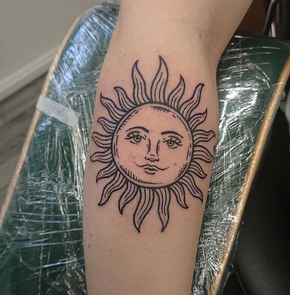 A sun tattoo with a face on a person's leg