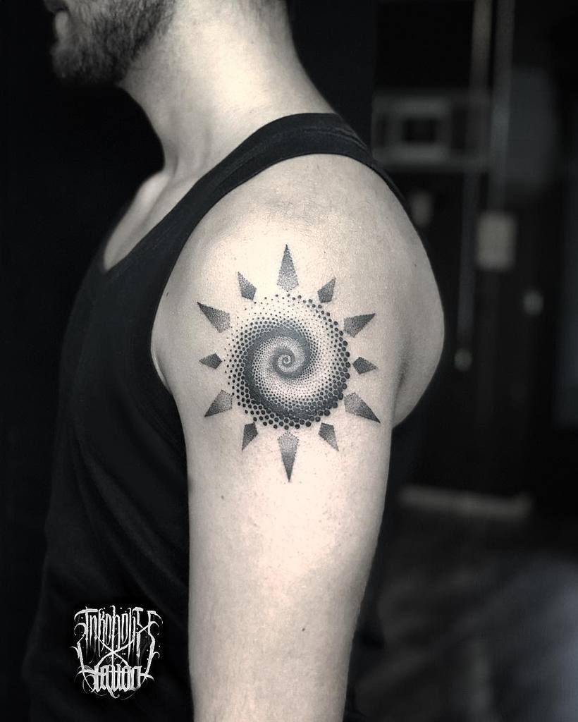A person with a detailed sun spiral tattoo on the upper arm