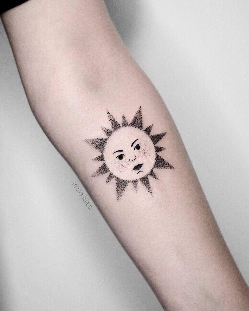 Tattoo of a sun with a human face on a person's forearm