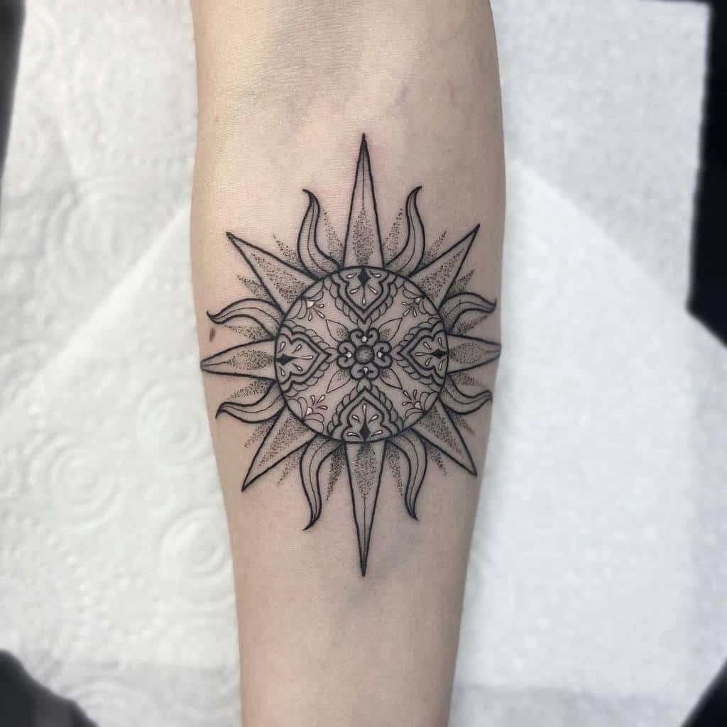 Delicate sun and mandala tattoo with intricate geometric and floral patterns, featuring sharp, pointed rays, placed on the forearm