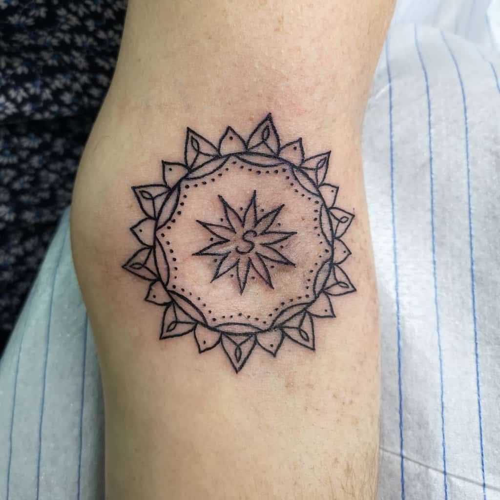 A geometric sun tattoo with a mandala design featuring a central star and leaves pattern
