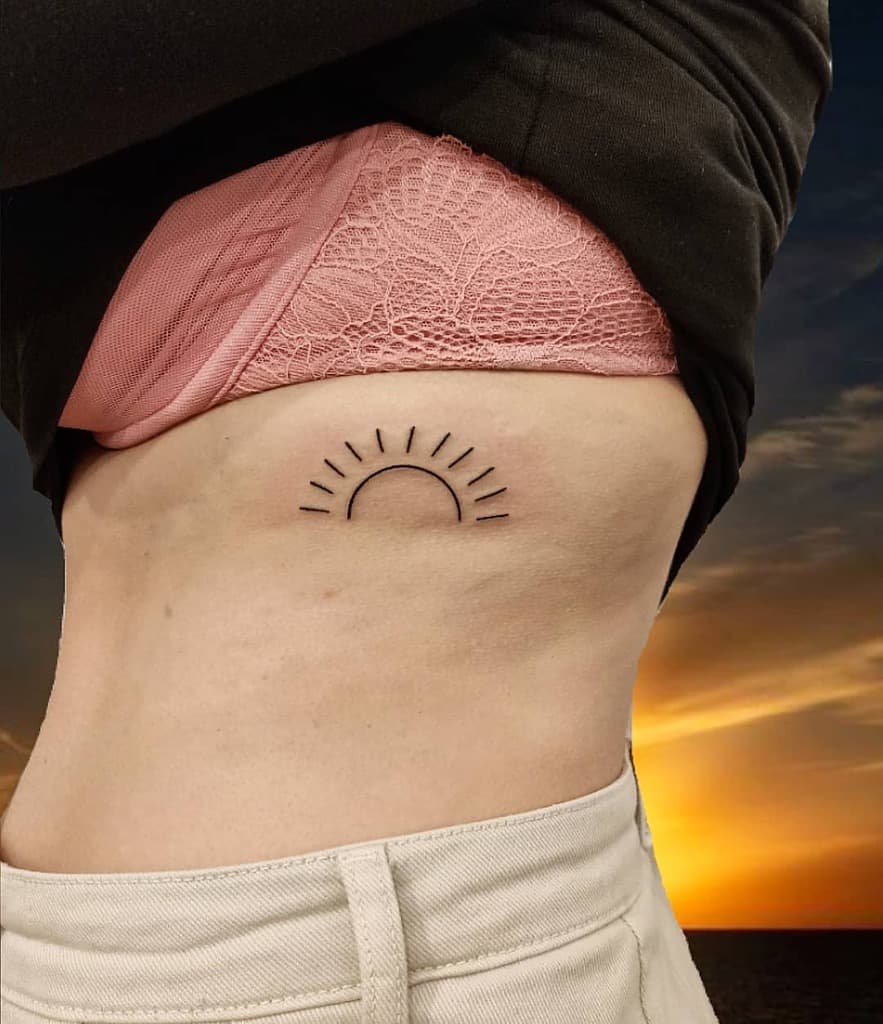 Minimalist sun tattoo on a woman's rib