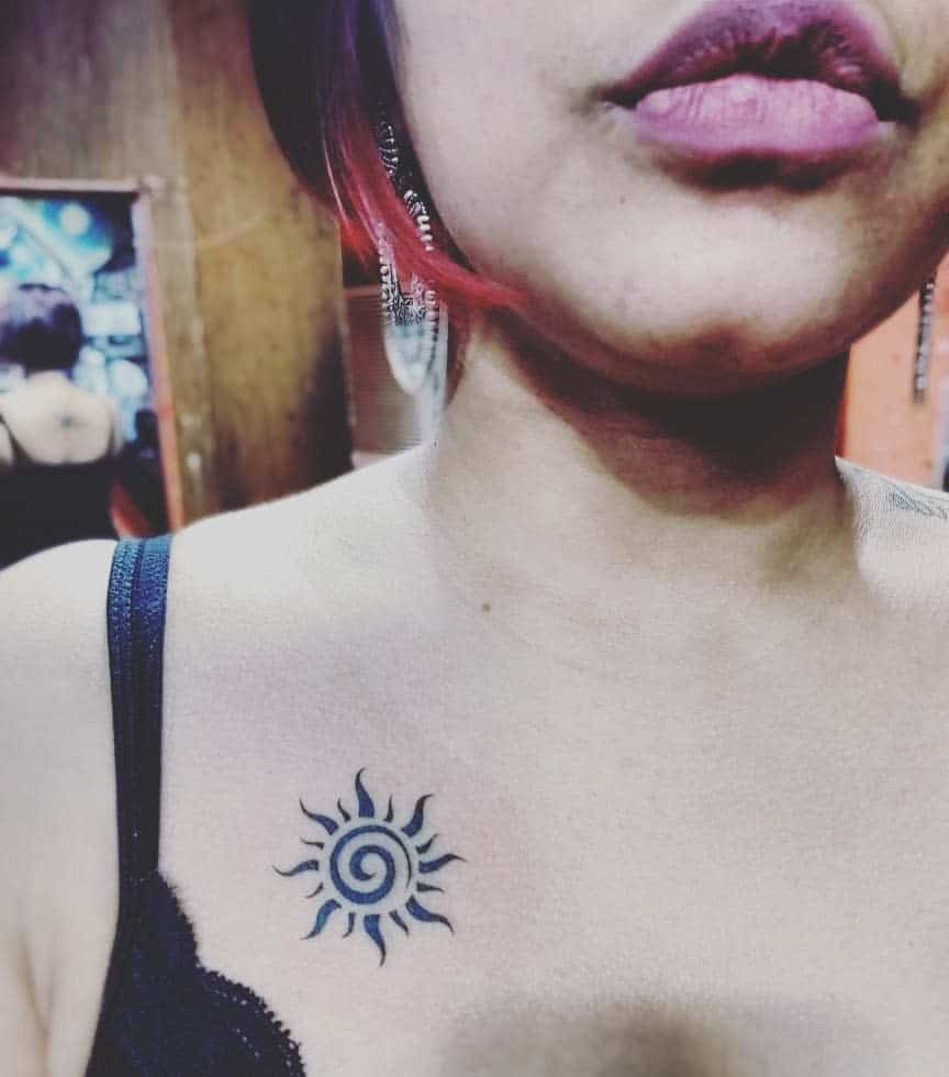 A woman with a sun tattoo on her upper chest
