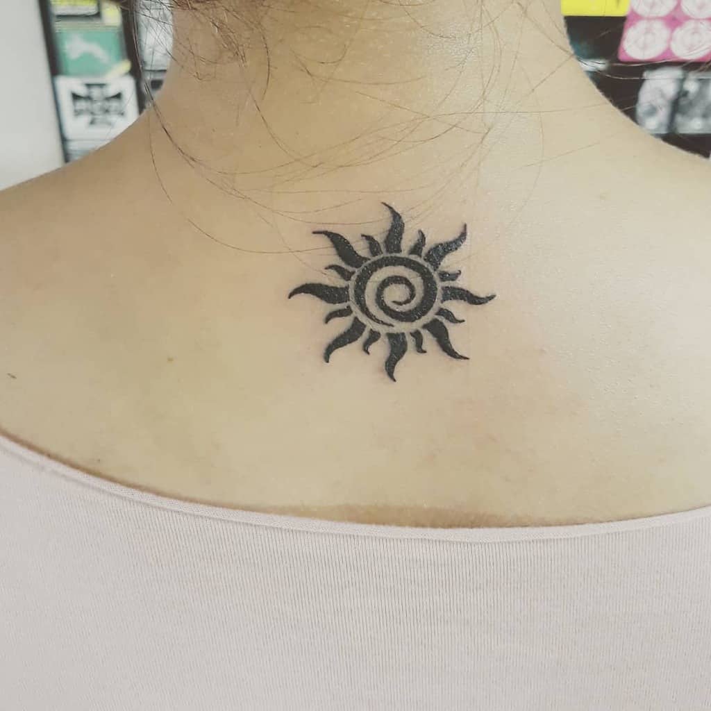 Tattoo of a black sun design on the upper back
