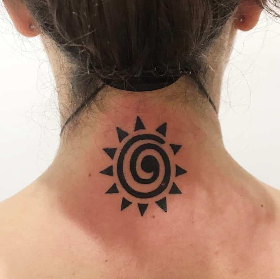 A black sun tattoo with a spiral center on the back of a neck