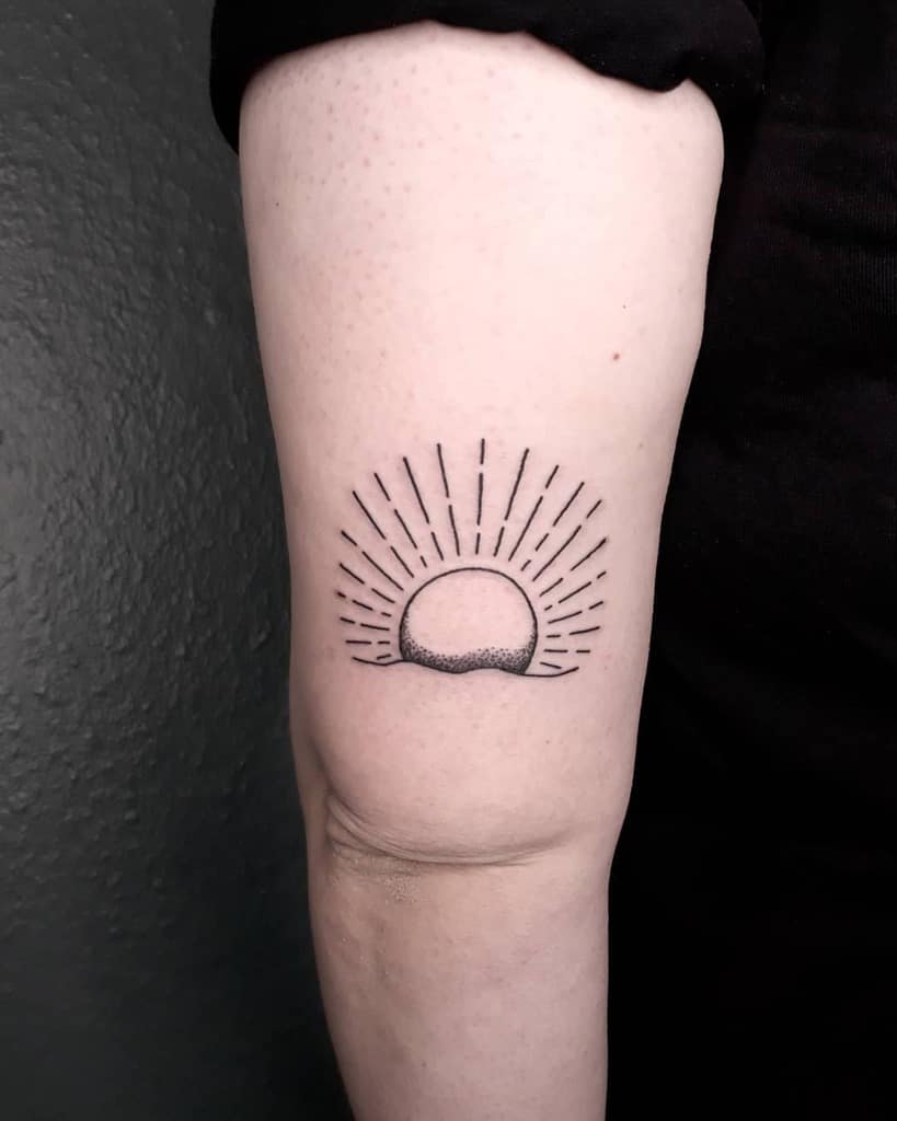 Tattoo of a sun with rays on the back of a person's arm