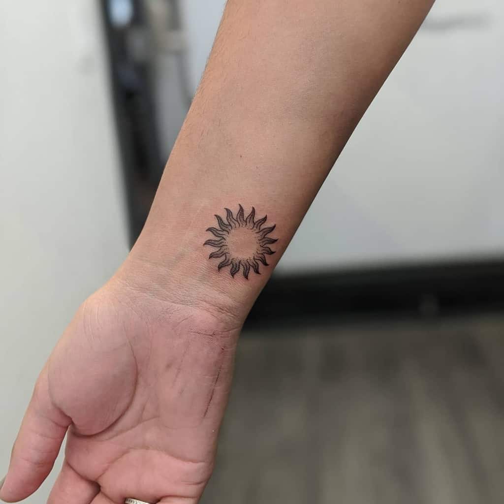 A sun tattoo with rays on the wrist