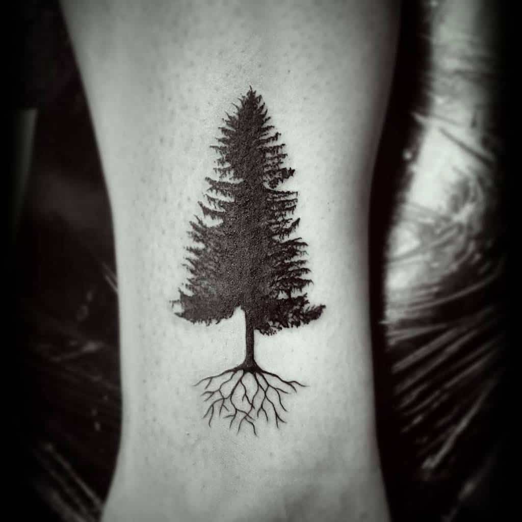 Black tattoo of a tree, its silhouette with deep roots etched gracefully on the skin
