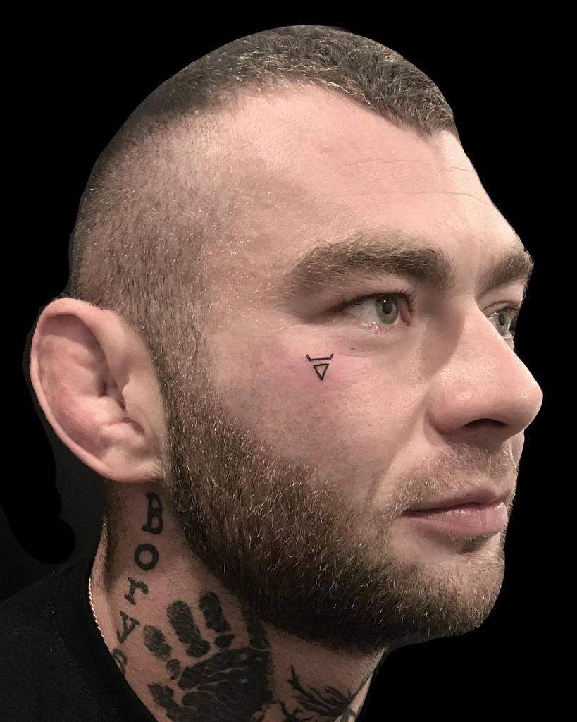 Man with a minimalist triangle tattoo under his eye