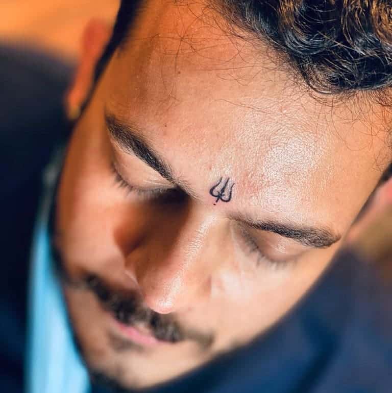 Man with a small Trishul (trident) symbol tattooed in the center of his forehead