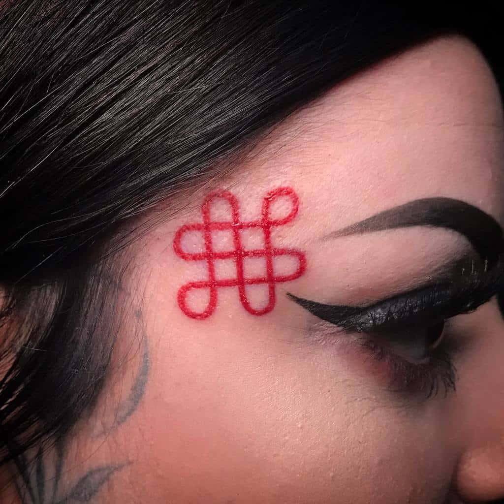 Woman's temple tattoo featuring a bold red geometric knot design