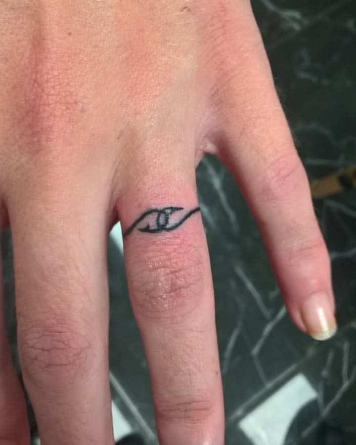 Minimalist black ring tattoo of two intersecting arrow line forming a loop