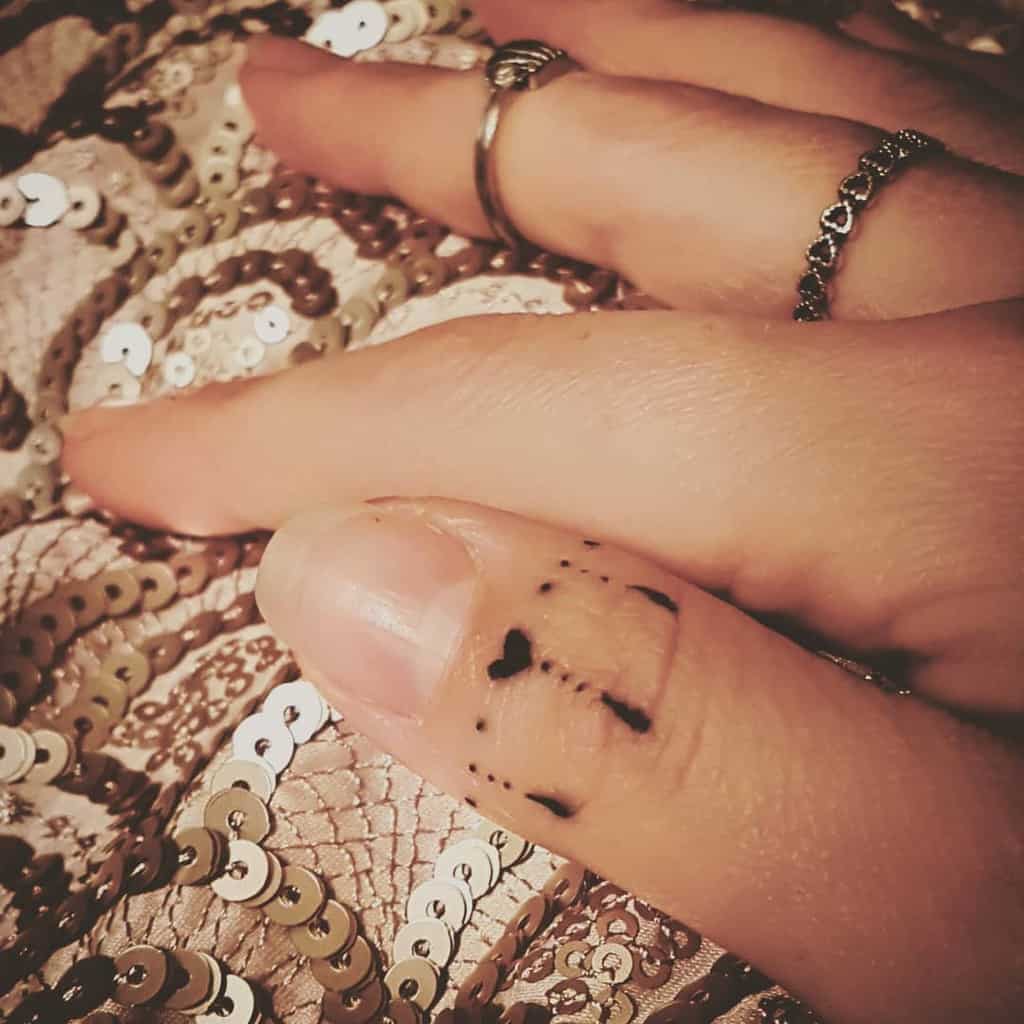Close-up of a small heart ring tattoo with fine dot works