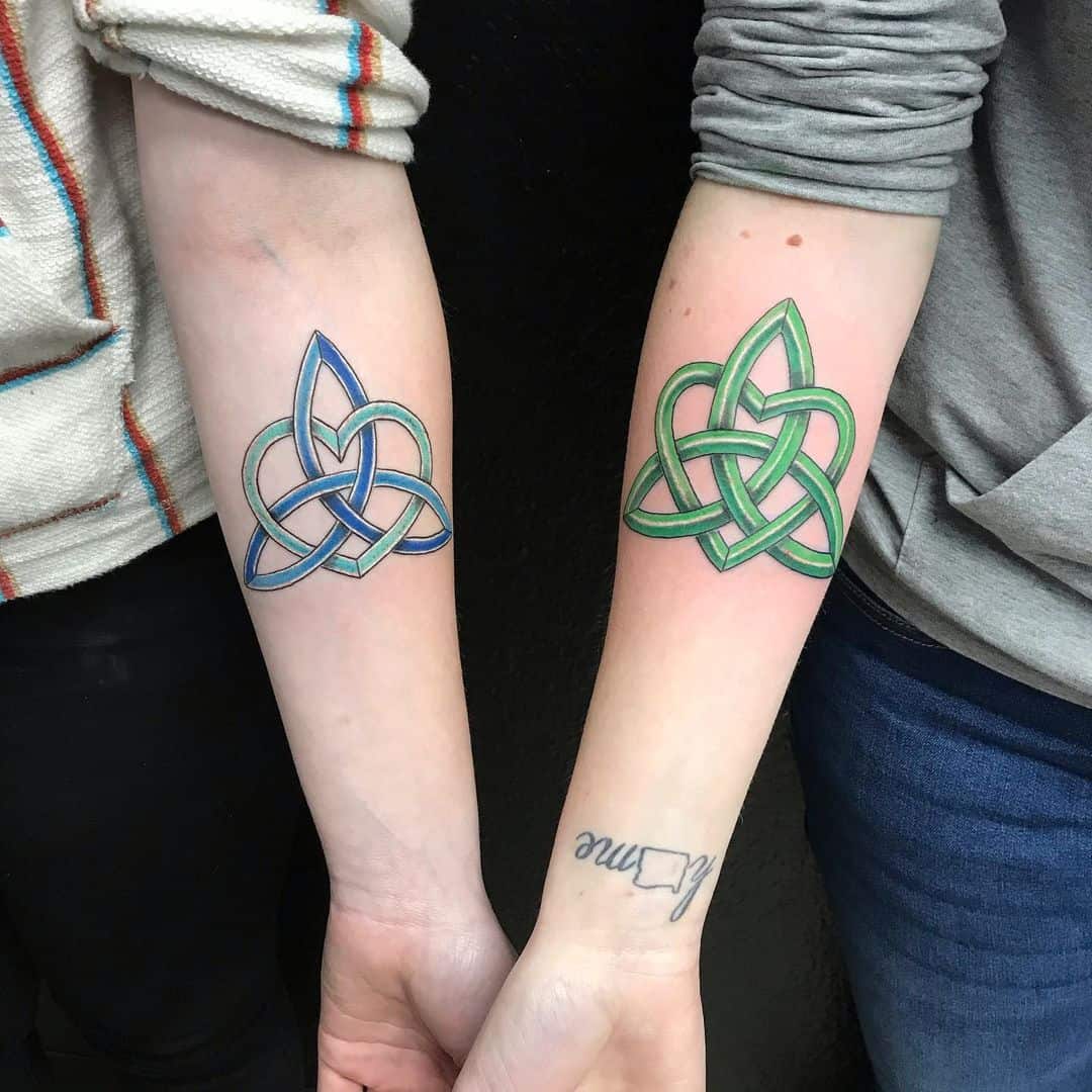Celtic knot tattoos on forearms, blue and green