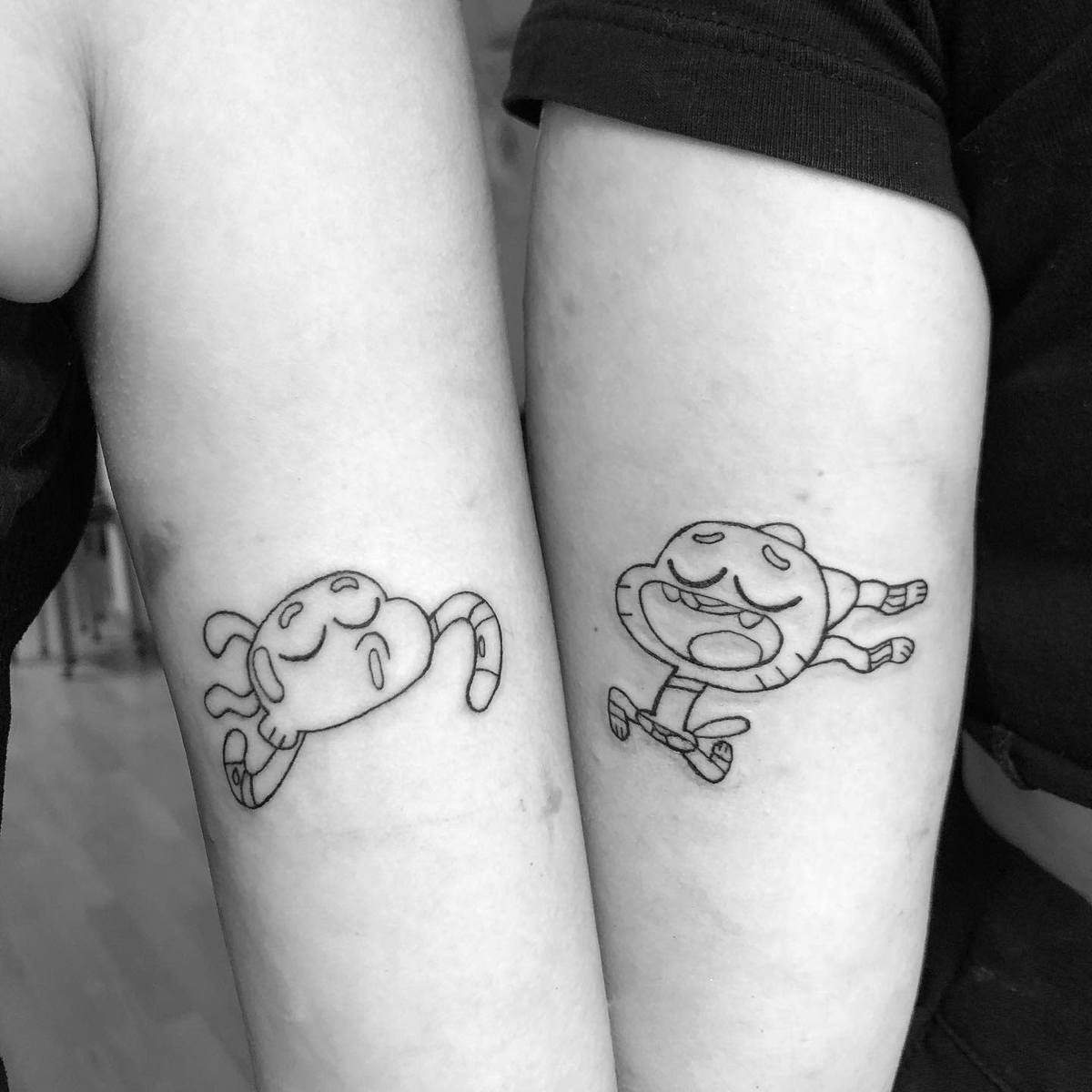 Matching cartoon cat tattoos on two arms in different poses