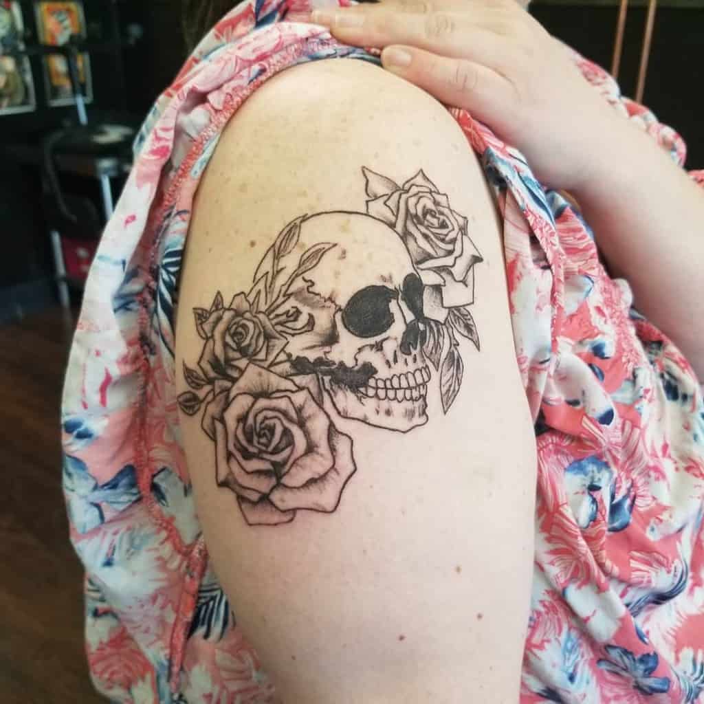 A woman with a floral skull tattoo on their upper arm