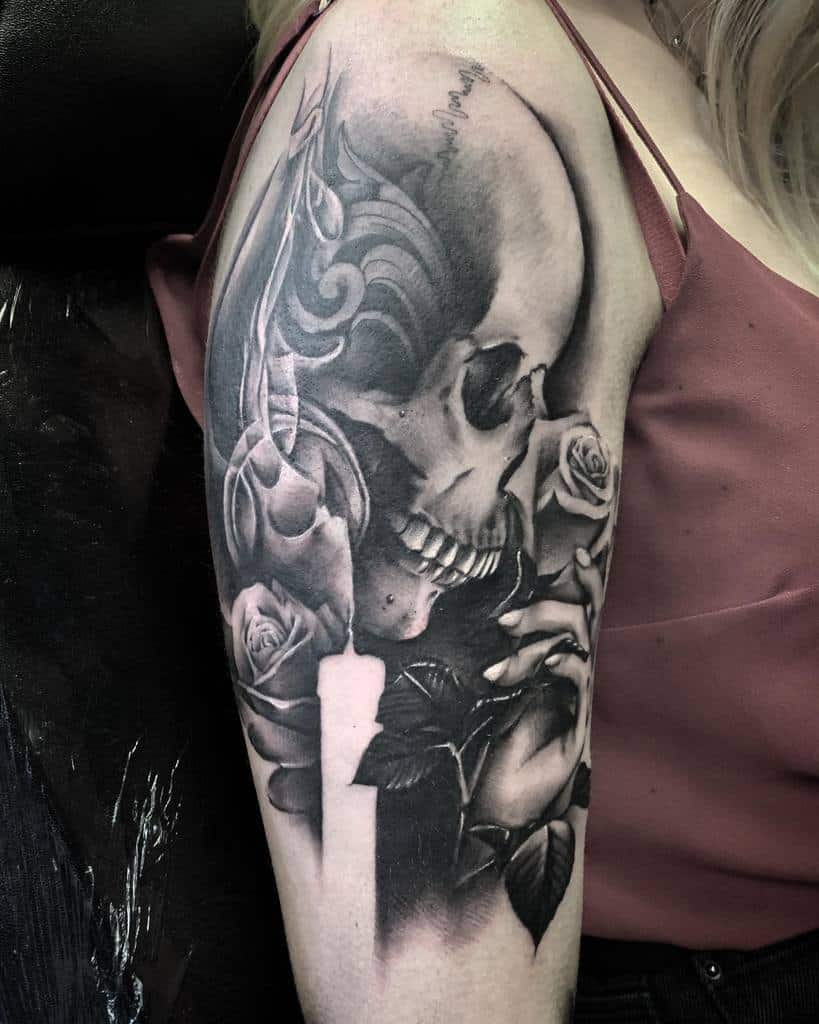Black and gray tattoo of a skull with roses on an upper arm