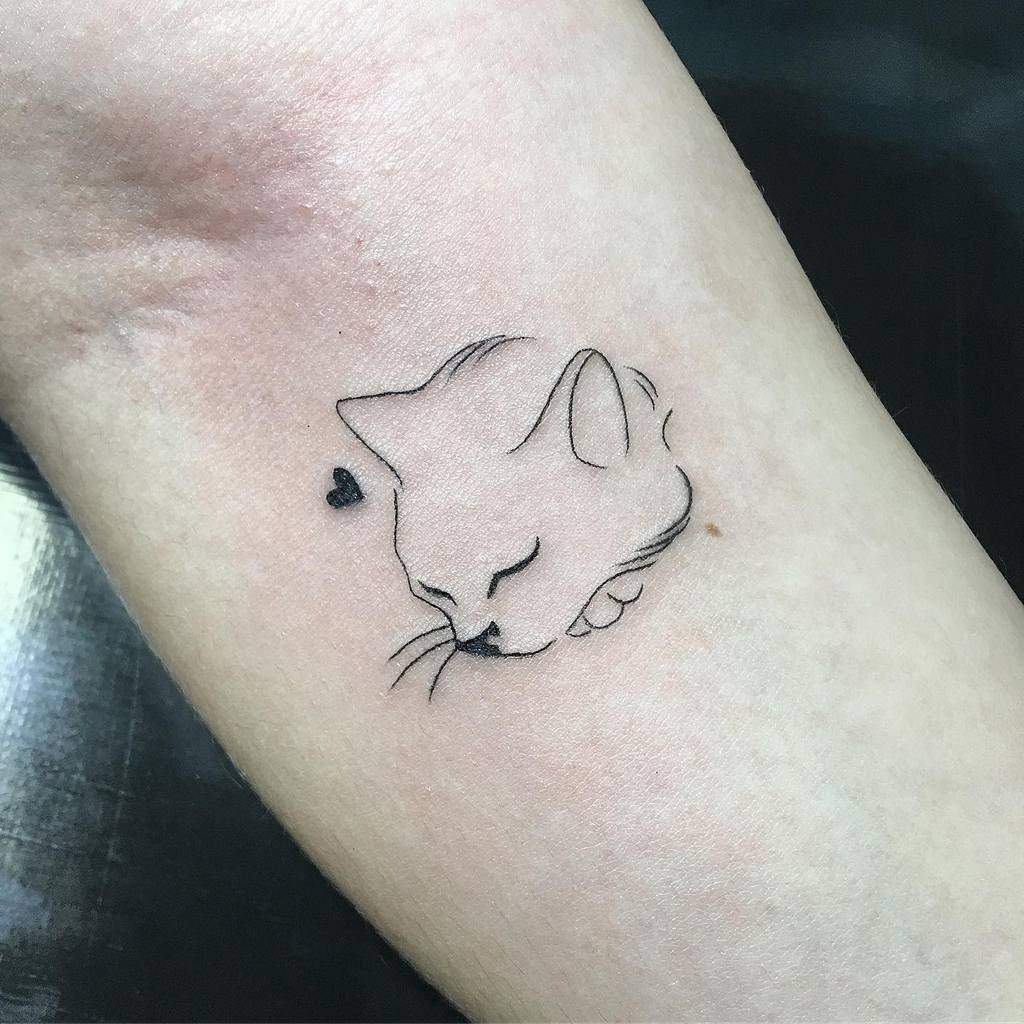 Minimalist cat design tattoo on light skin with a tiny heart beside the cat's head—a simple yet elegant choice for cat lovers