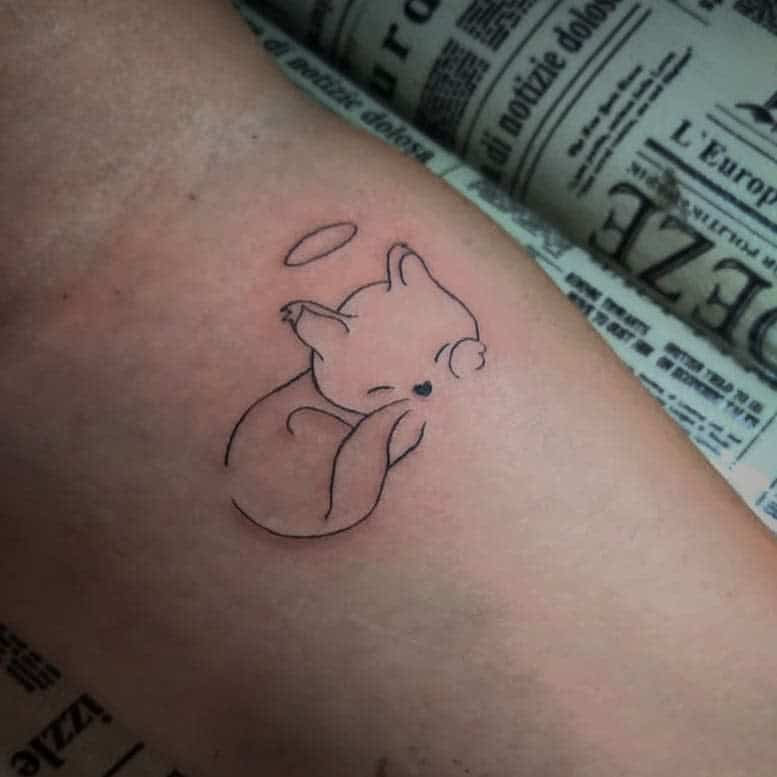 Tattoo of a peaceful sleeping cat with a halo above its head