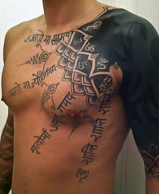 Man's bare chest and shoulder with extensive black and script-style tattoos