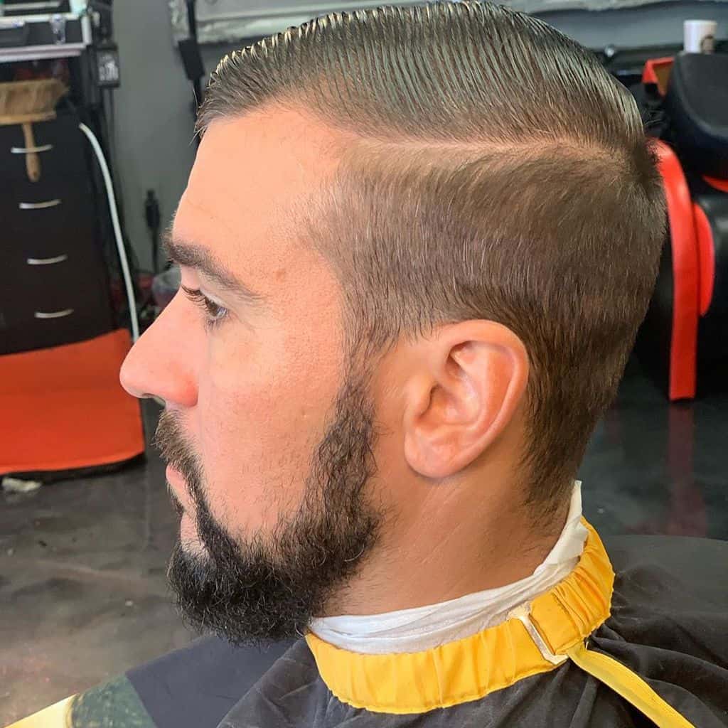 A slick comb-over style with high undercut and strip of hair running from the front to the back