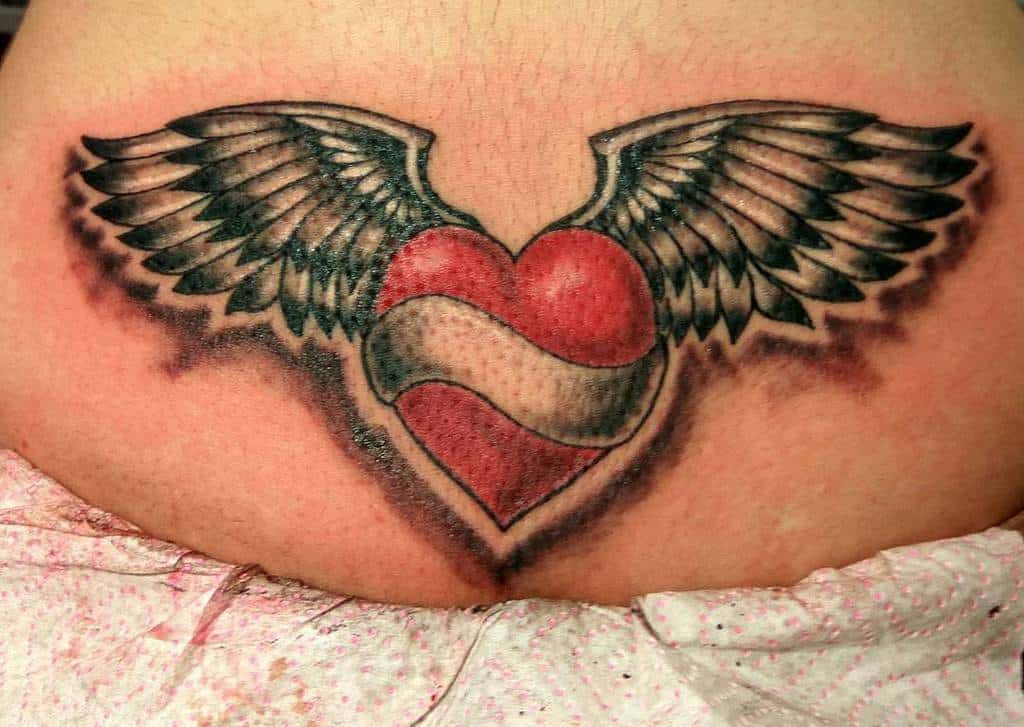 Heart with wings tattoo, featuring a striking red and white striped heart design