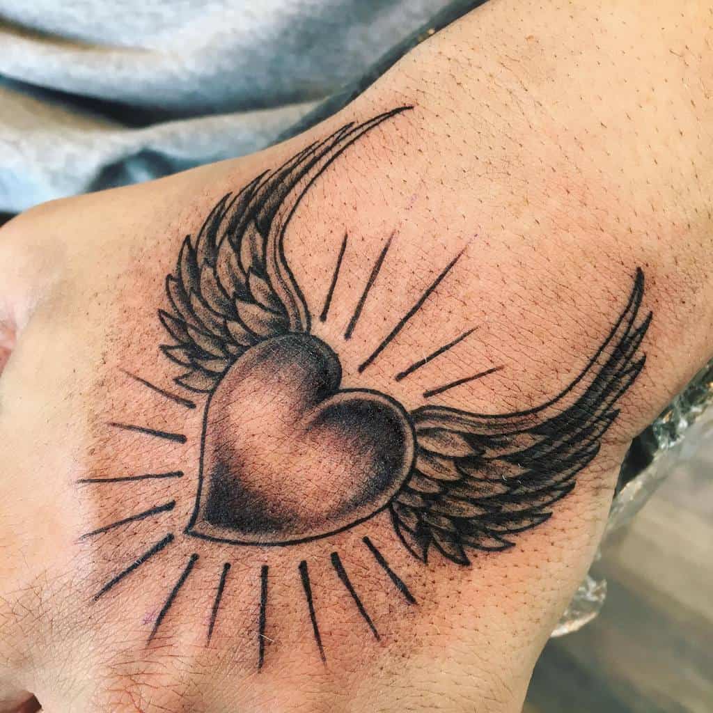 Heart tattoo on the back of a hand, with wings and rays emanating from it