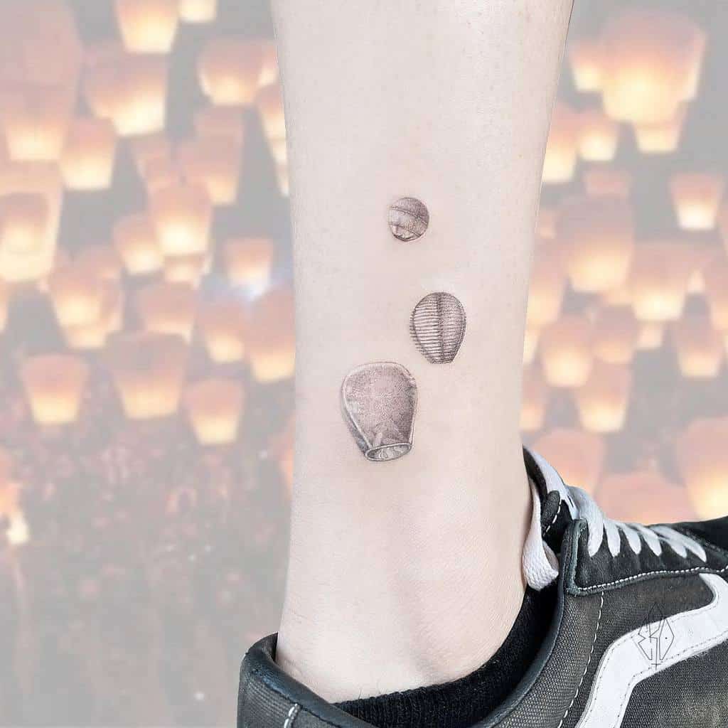 Tattoo of three lanterns on an ankle