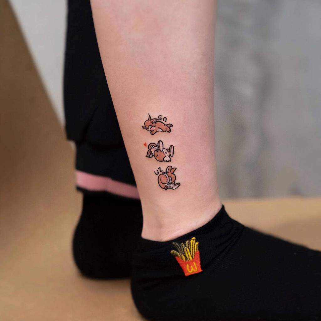Cartoon bunny tattoo in three playful poses on a woman's leg