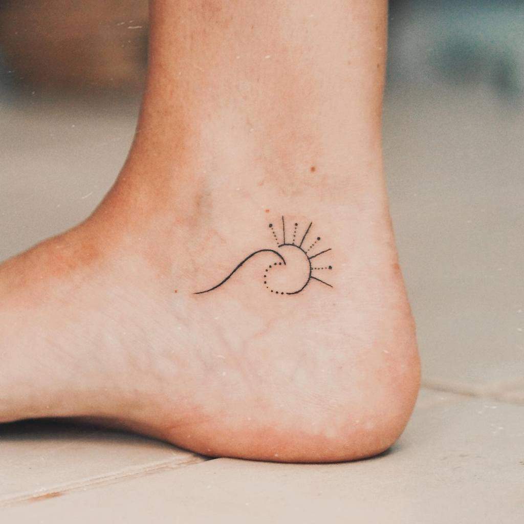 Minimalist tattoo of a wave with a sun on an ankle