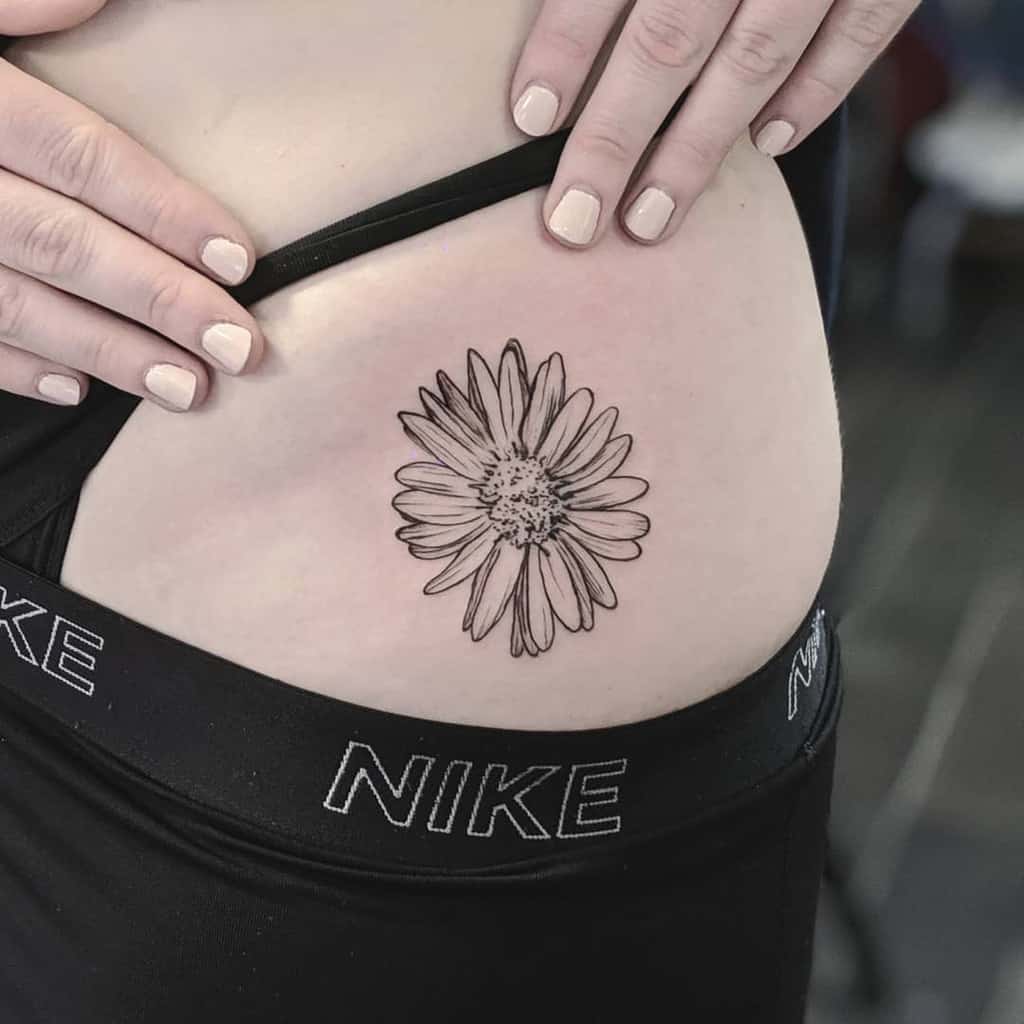 Black and white aster tattoo on a person's hip