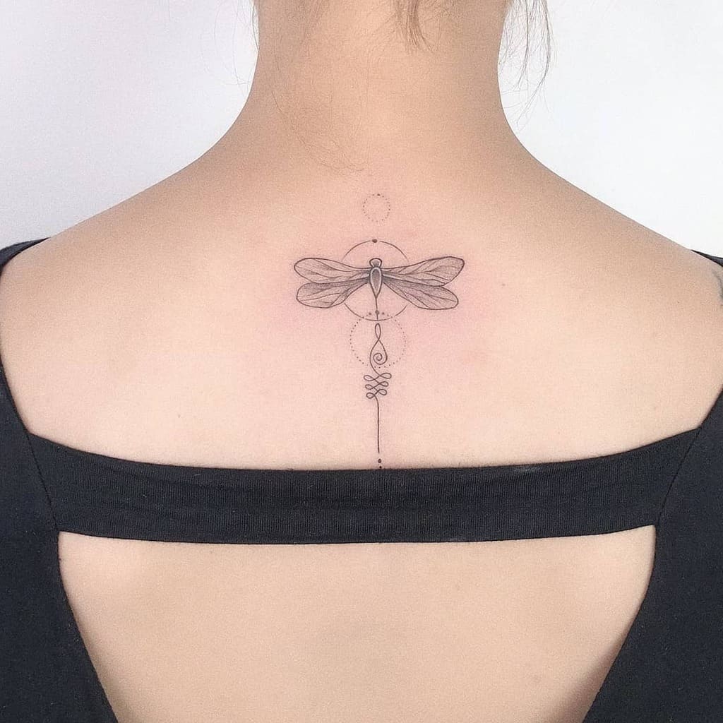 Minimalist dragonfly tattoo on a woman's upper back, featuring geometric lines and shapes