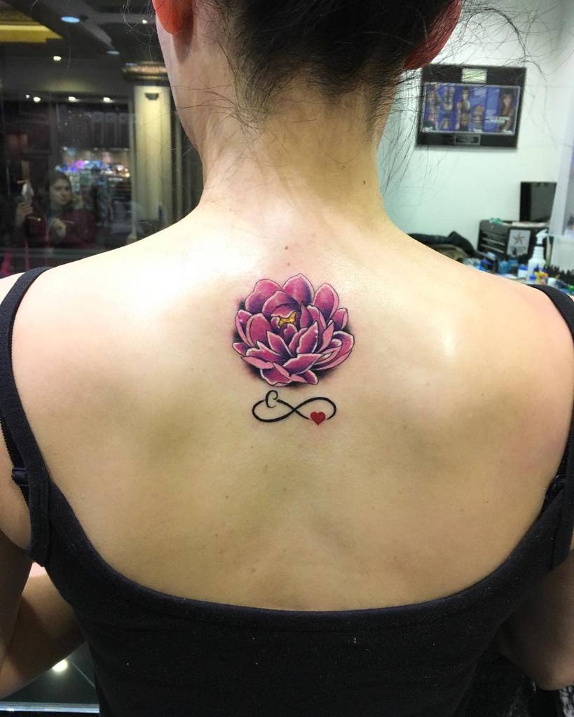 Woman with a pink flower tattoo and heart on her upper back