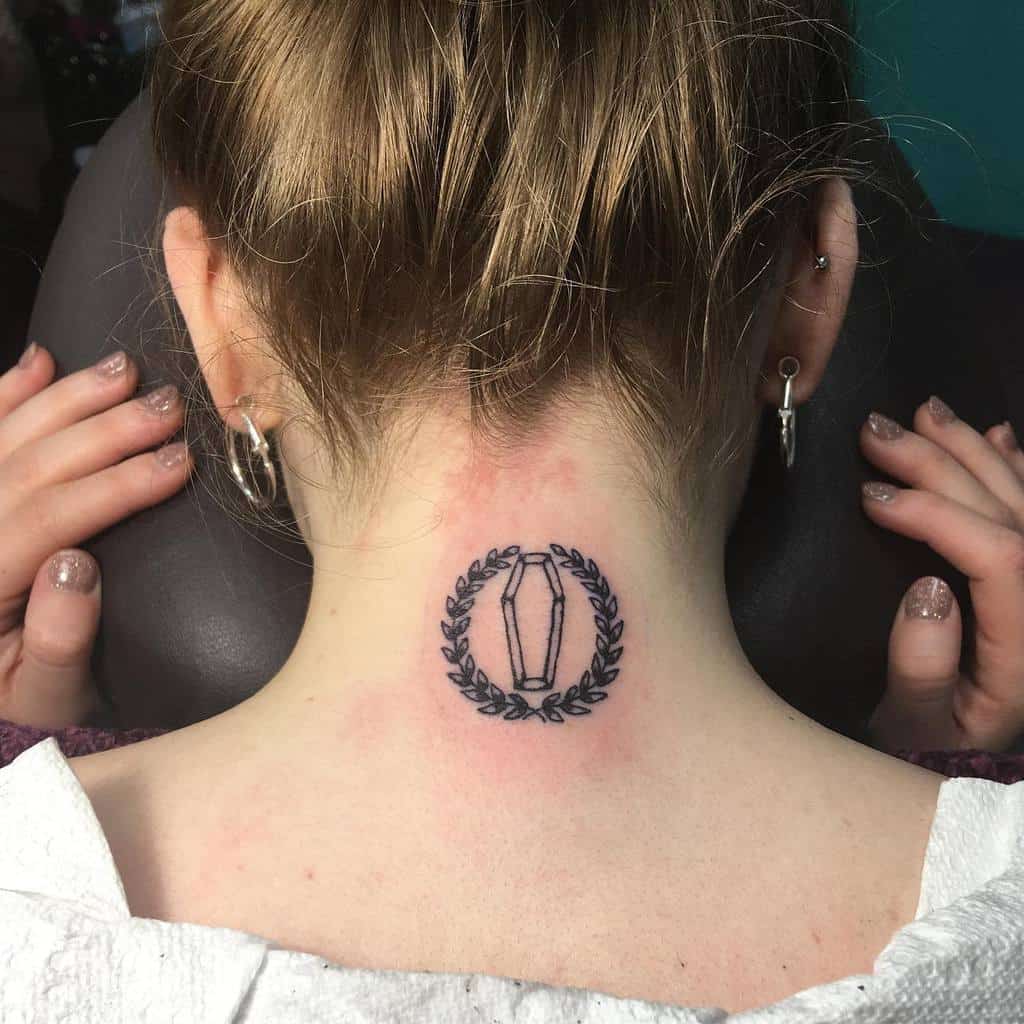 Neck tattoo featuring a coffin surrounded by a laurel wreath on the back of neck