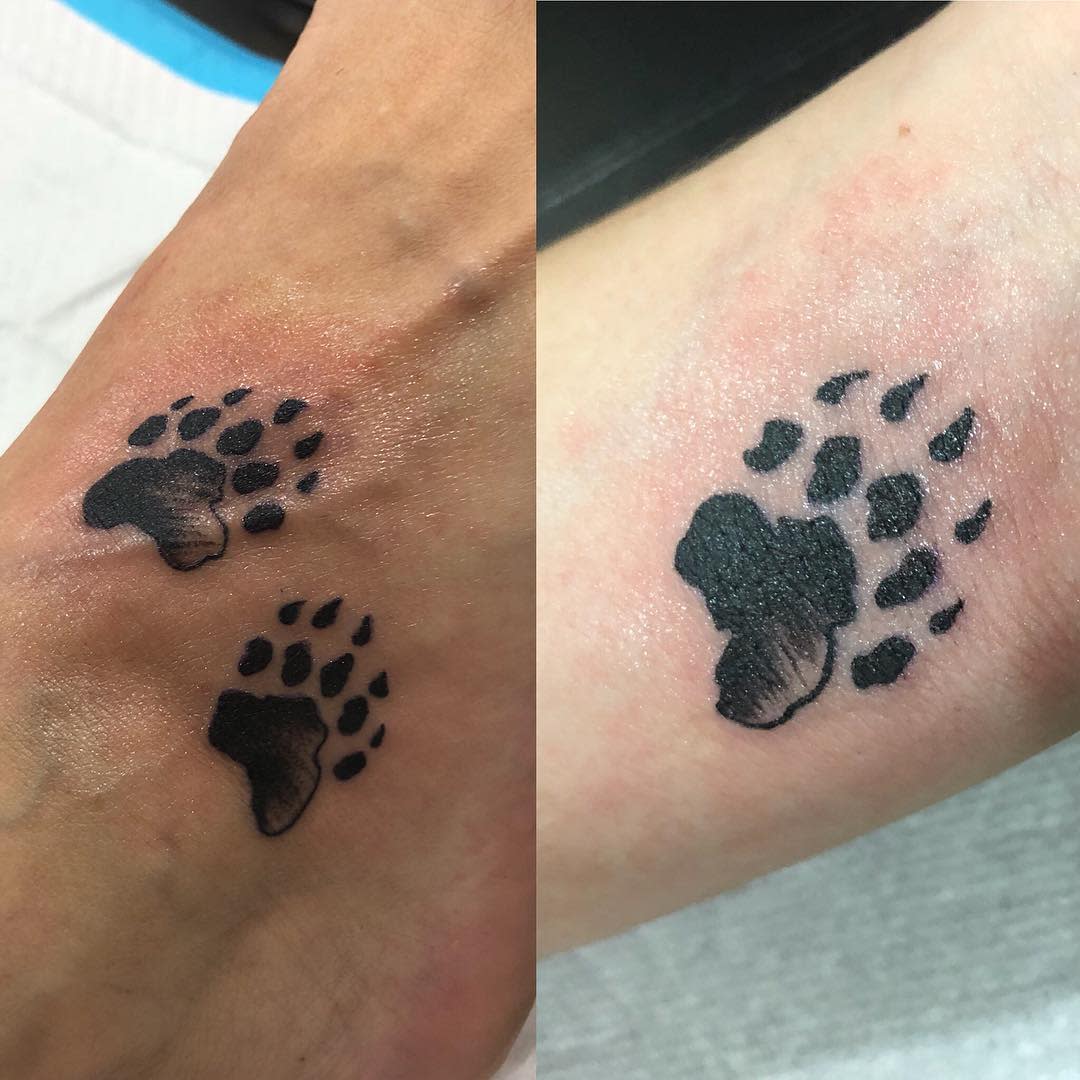 Two bear pawprint tattoos on skin, one faded, the other freshly inked
