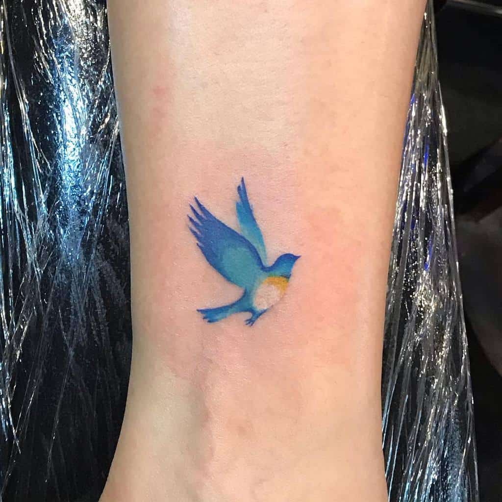 A small blue bird tattoo on an ankle