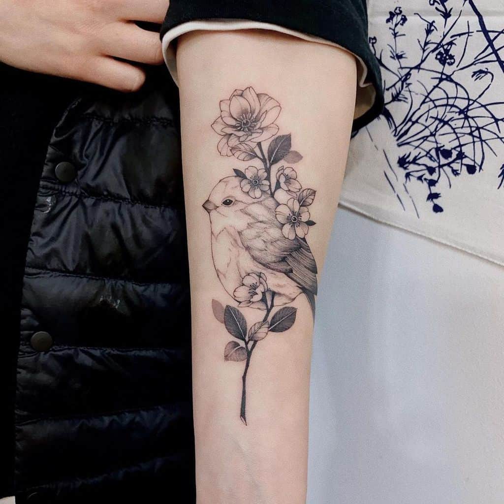 Tattoo of a bird and flowers on a forearm
