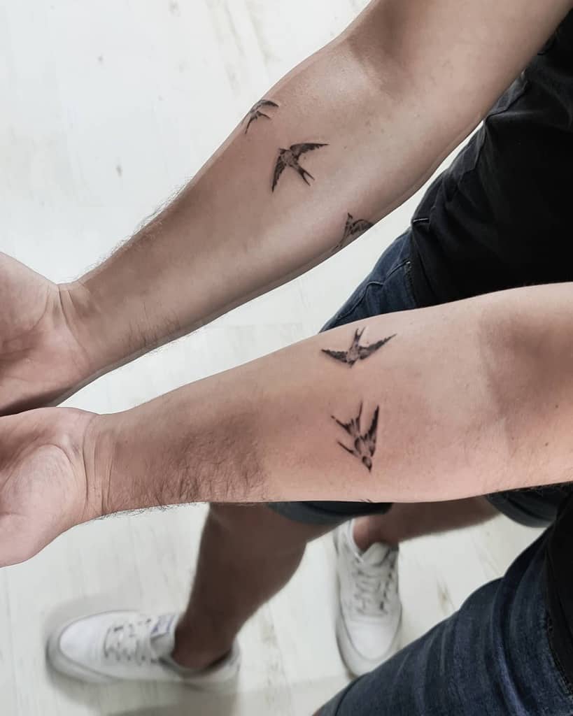Two forearms with multiple small bird tattoos 