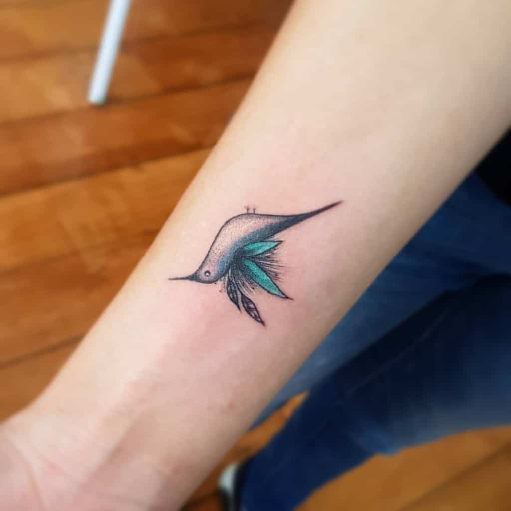 Tattoo of a stylized bird with blue wings on a forearm
