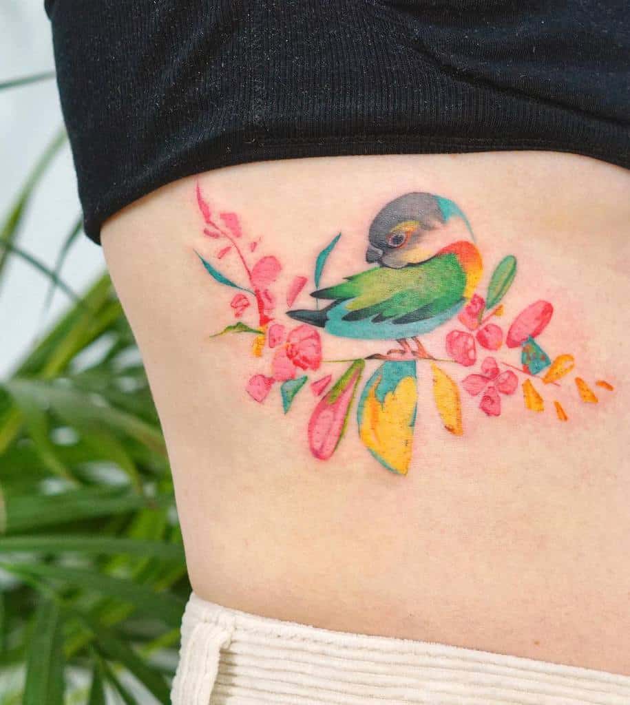 Colorful bird and flowers tattoo on a person's side near the waist