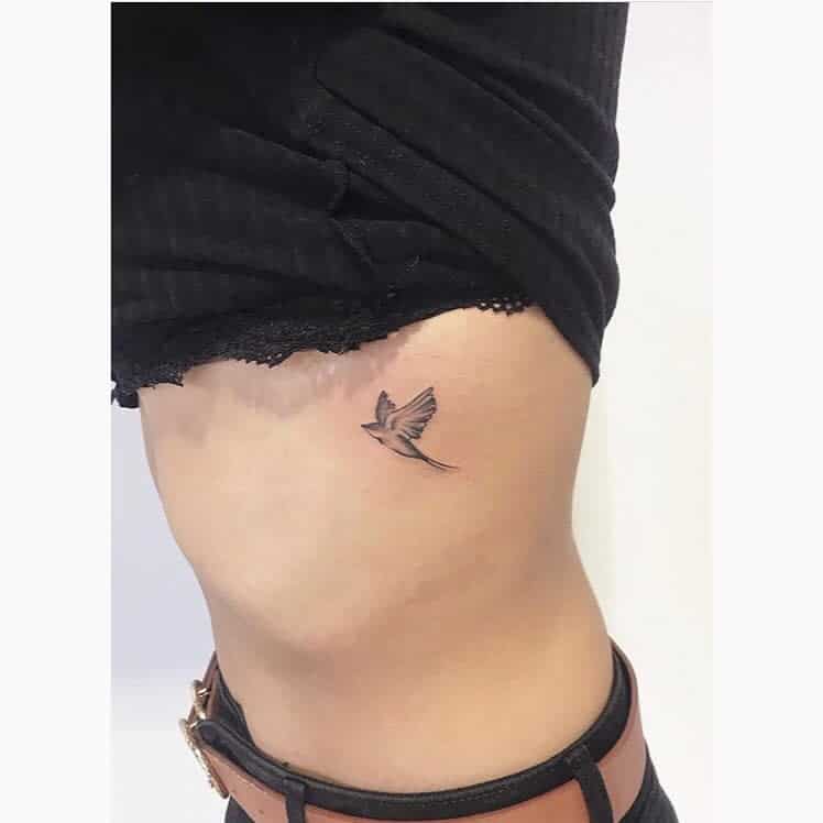 Small swallow tattoo on a side torso near the ribcage