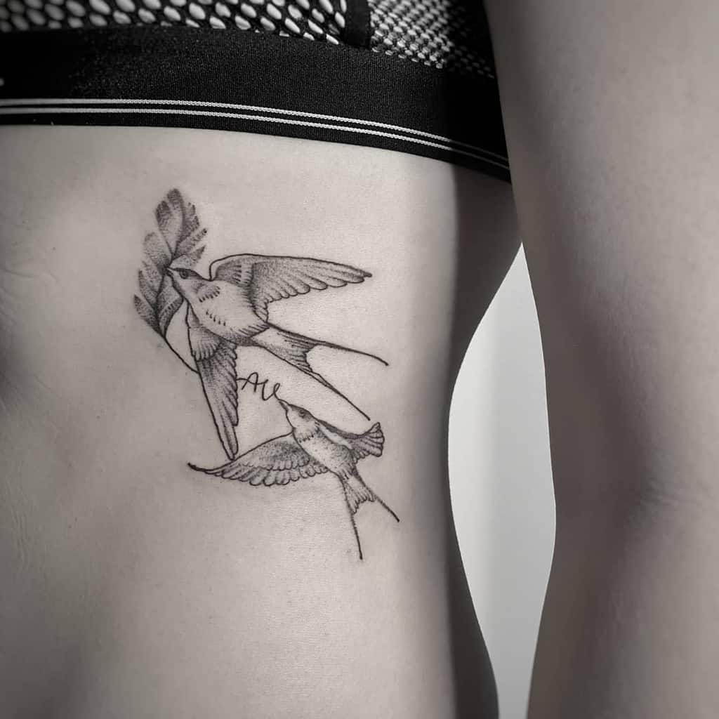 Two birds tattooed on a person's side