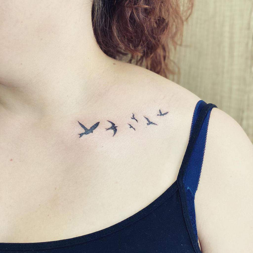 Shoulder tattoo of six birds in flight on a woman
