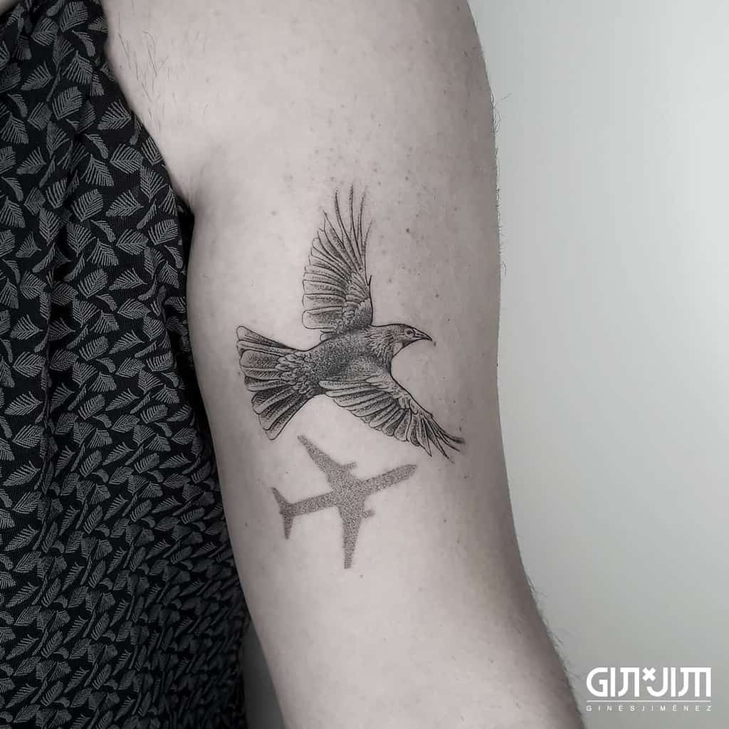 Arm tattoo of a bird flying above a plane silhouette