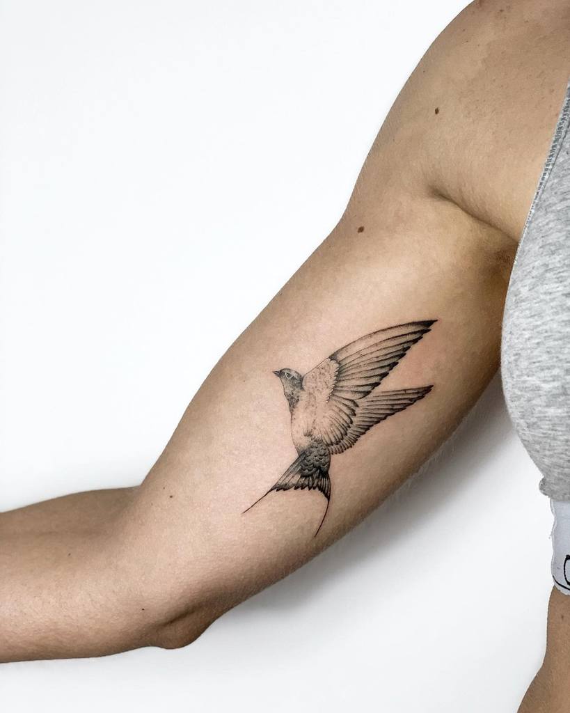 Tattoo of a bird in flight on a woman's upper arm
