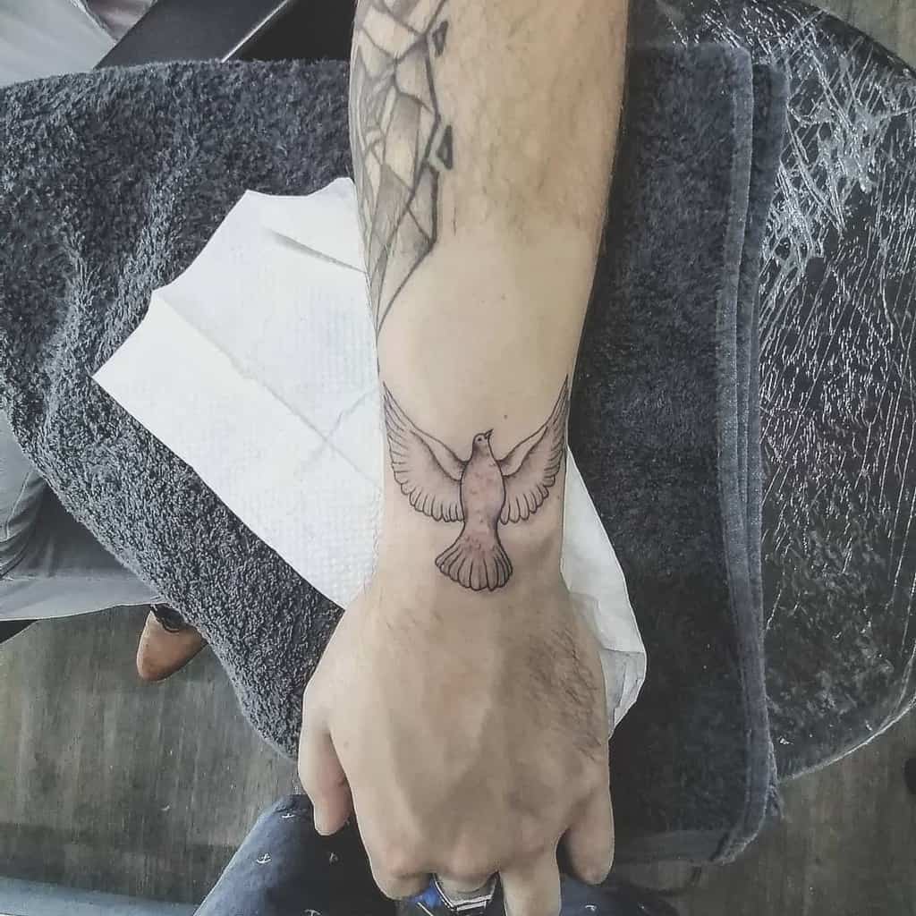Forearm tattoo of a flying dove with outstretched wings on a wrist