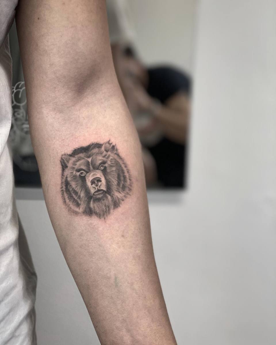 Tattoo of a roaring bear's head on a person's inner forearm