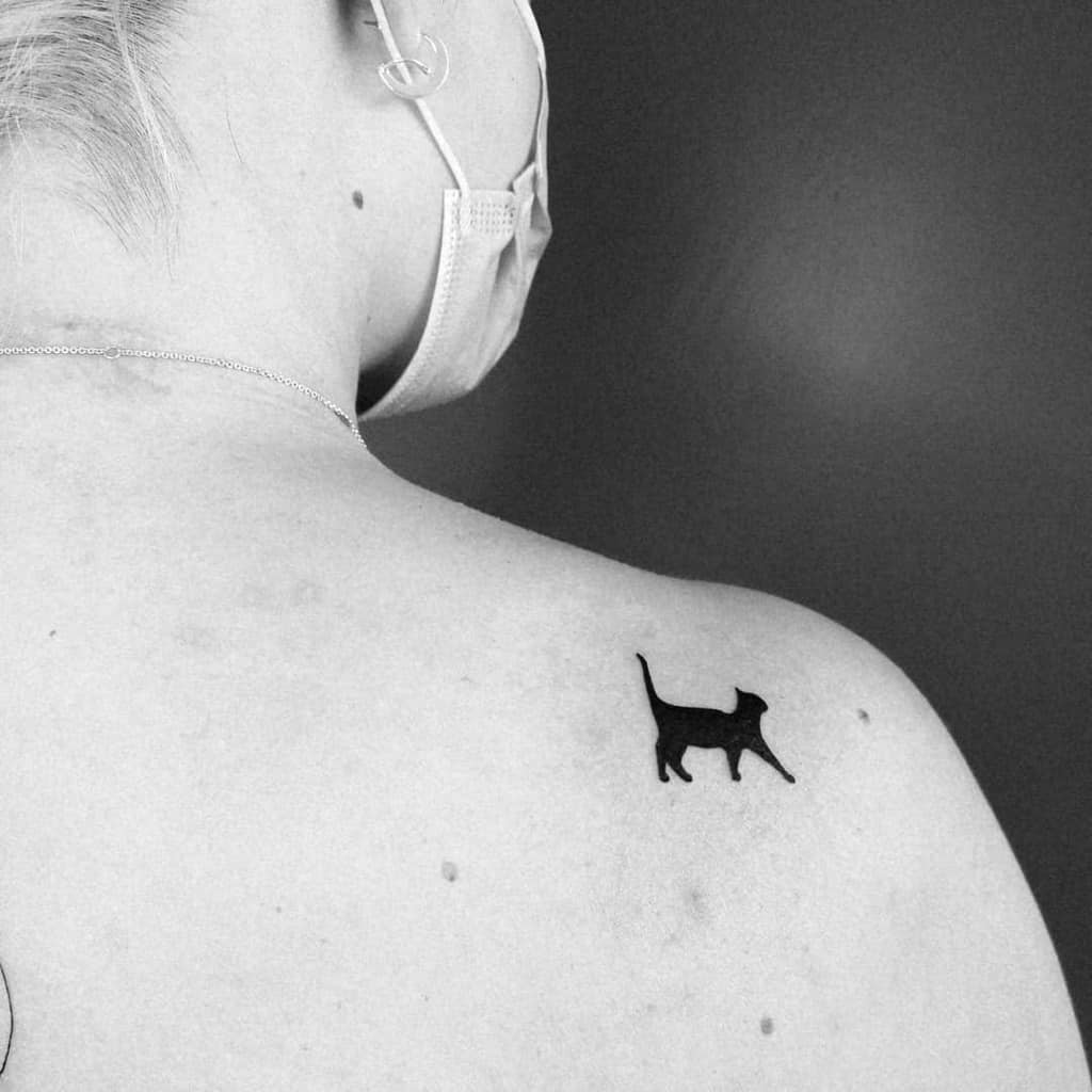 Sleek cat silhouette tattoo on the upper back