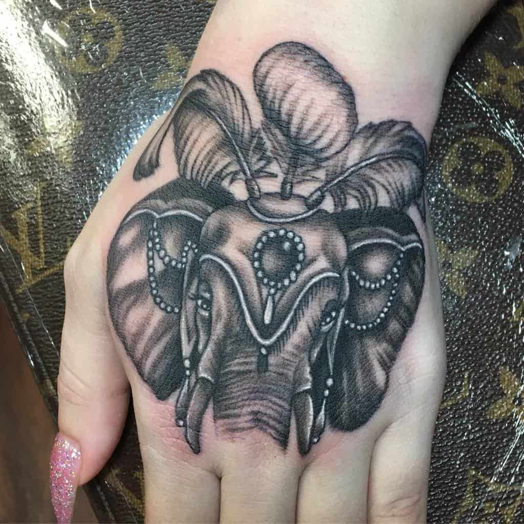 Detailed black elephant hand tattoo with ornamental designs and feather accents, showcasing elegance and strength