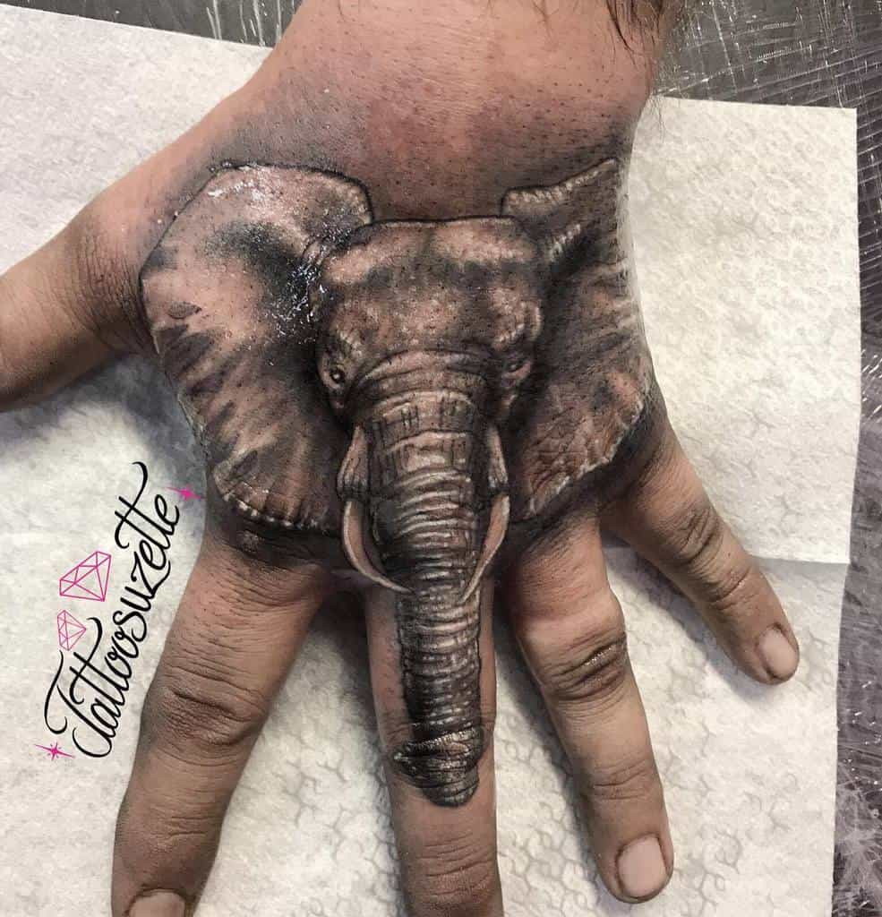 A realistic elephant head tattoo on the back of a hand